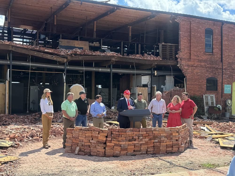 On September 30, 2024, former president Donald Trump speaks to the media in Valdosta, Ga., surrounded by local officials including Mayor Scott James Matheson (third from left) and supporters including former U.S. Senator Kelly Loeffler (far left).