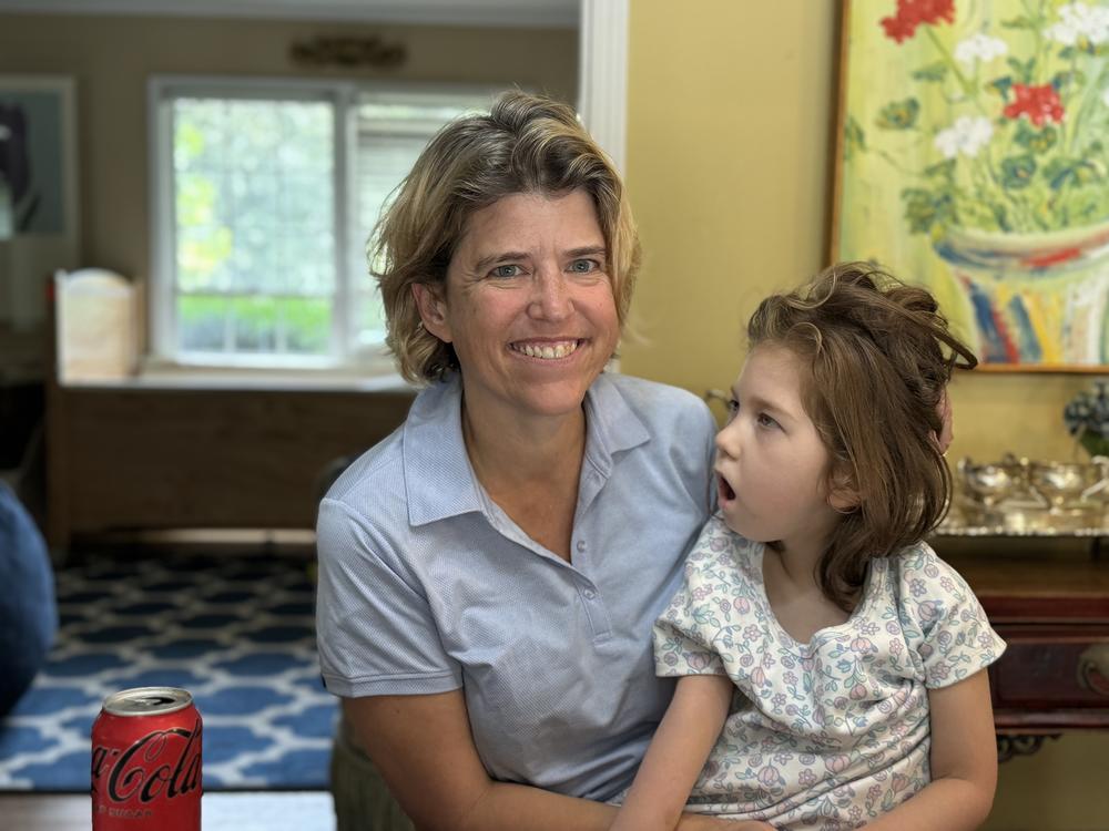 Mary Cota Reed holding her 8-year-old daughter Catherine in their Atlanta home. Ambria Burton/GPB News