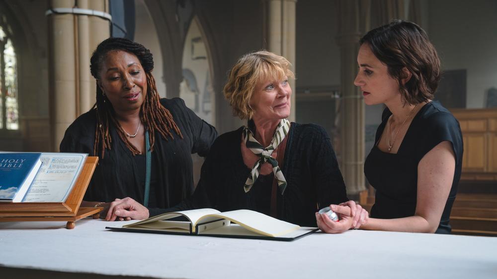 Three women looking at a book in a church.