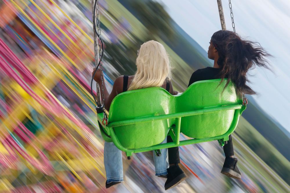 Two fairgoers ride atop a large swing ride above  the Georgia National Fair in Perry, Georgia, on Saturday, Oct. 5, 2024.  The Georgia National Fair's midway contained a variety of different attractions, food stalls, and games for fair attendees. (Photo/Felix Scheyer)