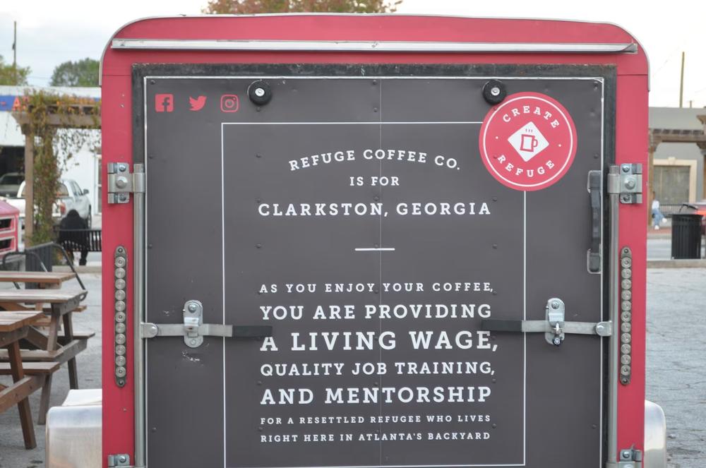 Words painted on a trailer in the parking lot of Refuge Coffee Company's Clarkston, Georgia, describe how buying the shop's coffee help's many local resettled refugees.  (Allen Siegler / Healthbeat) 