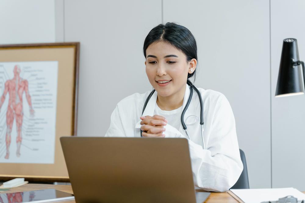 A health care worker sits at a laptop