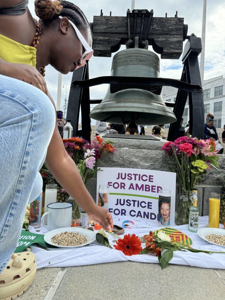 Kianta Key placed a hair bead on a makeshift altar set up as a tribute to Amber Nicole Thurman and Candi Miller on Saturday near the state Capitol. Key said the hair bead represents the “beauty of who they were.” Jill Nolin/Georgia Recorder