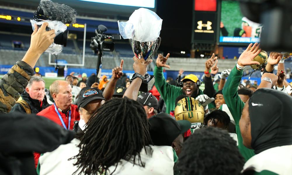 A high school football team holding up a trophy.