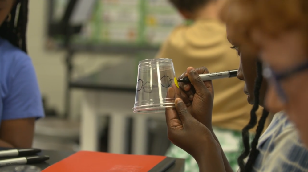 Elementary student draws on cup.