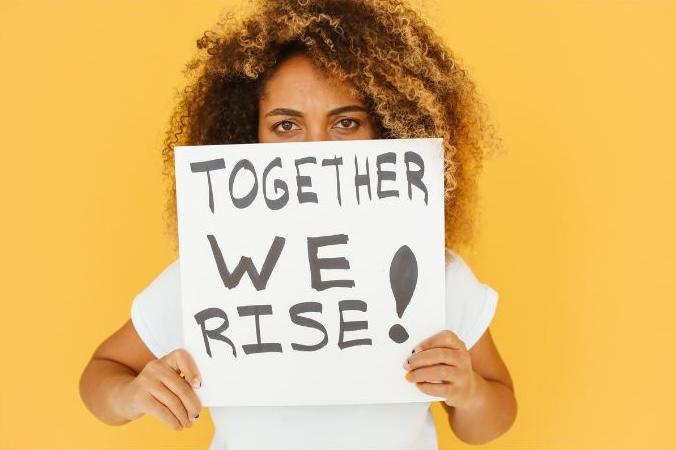 Woman with 'Together We Rise' poster.