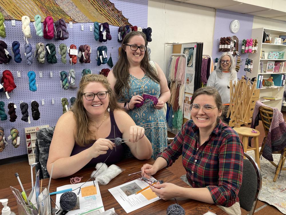 Four women learning to knit in a yarn shop