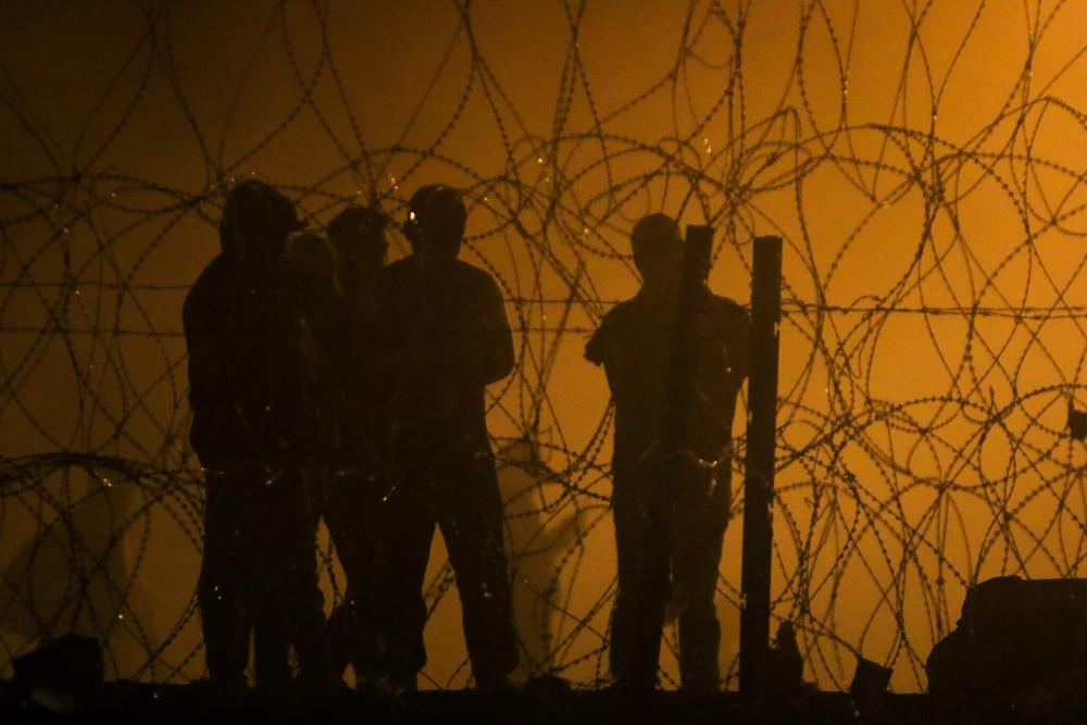  Migrants wait throughout the night on May 10, 2023, in a dust storm at Gate 42, on land between the Rio Grande and the border wall, hoping they will be processed by immigration authorities before the expiration of Title 42. (Photo by Corrie Boudreaux for Source NM)