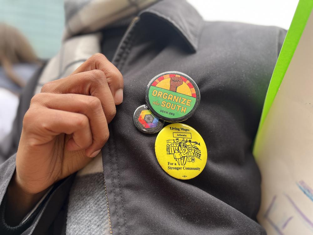 A labor organizer wearing pins that say "organize the south" and "living wages for a stronger community".