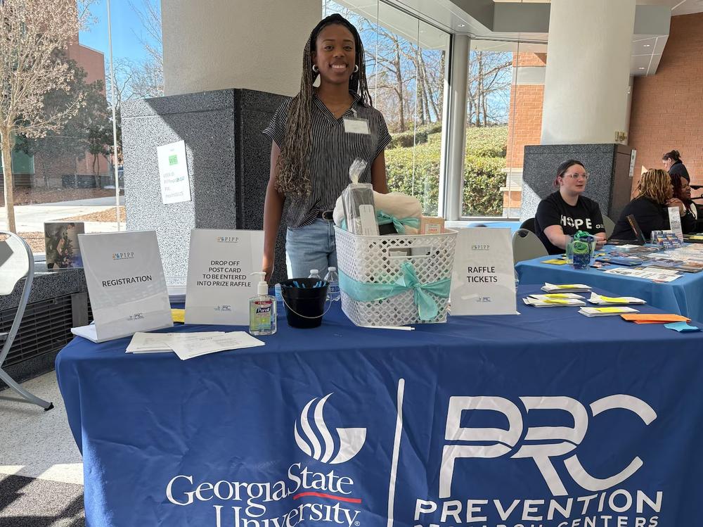 Makayla Jackson, a master of public health student at Georgia State University, poses behind a table at the college’s Health and Wellness Expo at its Clarkston Campus on Wednesday. (Allen Siegler / Healthbeat) 