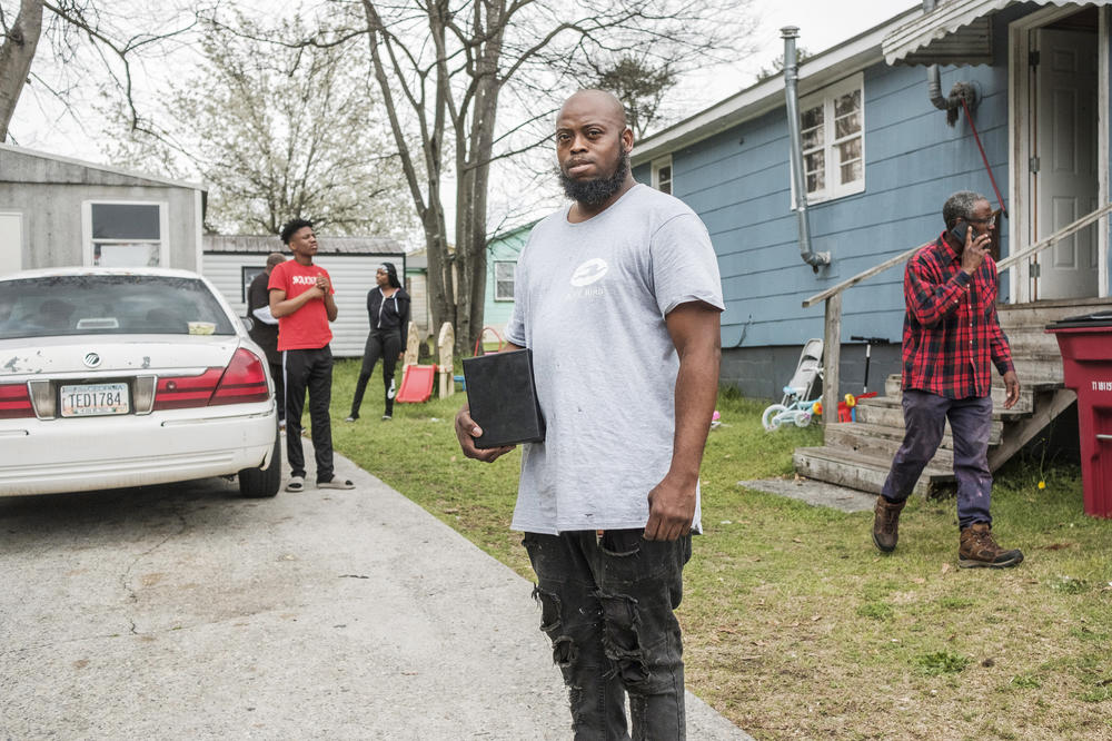 Carlos Ross holds the box containing the ashes of his son, Carmelo Ross, who was 15 when he was shot and killed at the same spot two other people were killed just a couple of years prior in Macon’s Anthony Homes, known to residents as Bird City.