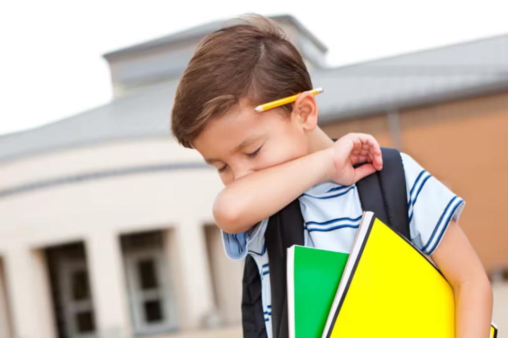 Young boy coughs or sneezes into crook of elbow