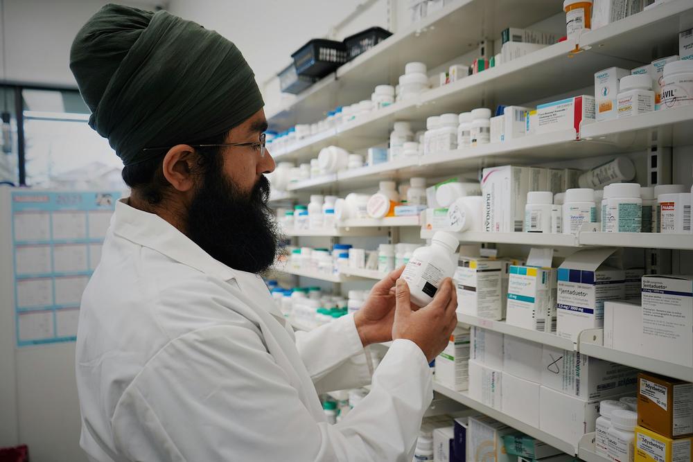 A pharmacist holds a bottle of pills and examines it