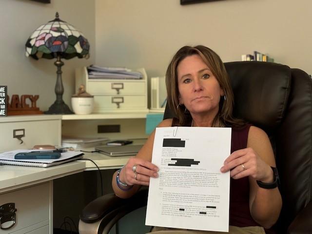 Tracy Hooper holds a redacted letter from her insurance company