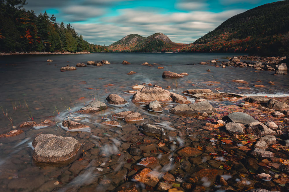 A bubbling, rocky pond with hills and mountains in the distance