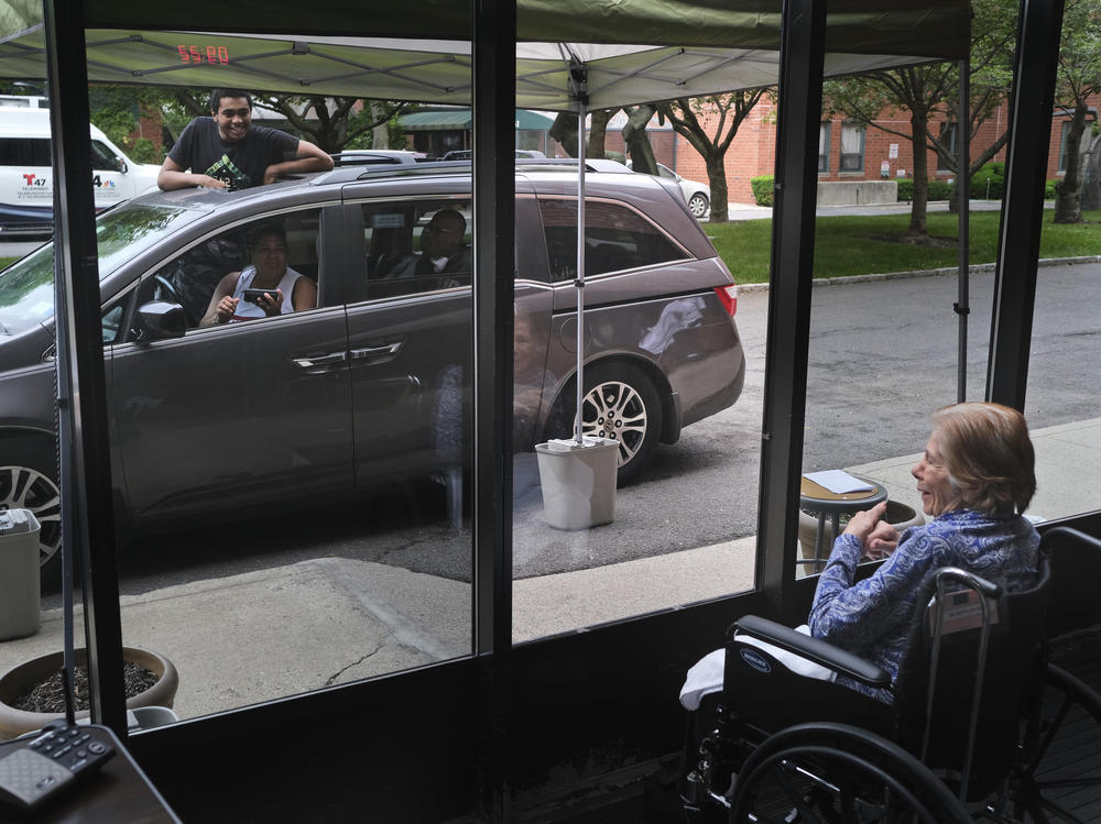 Gloria DeSoto, 92, right, visits with her family, in their car, from a window of the Hebrew Home at Riverdale, in New York, last month.