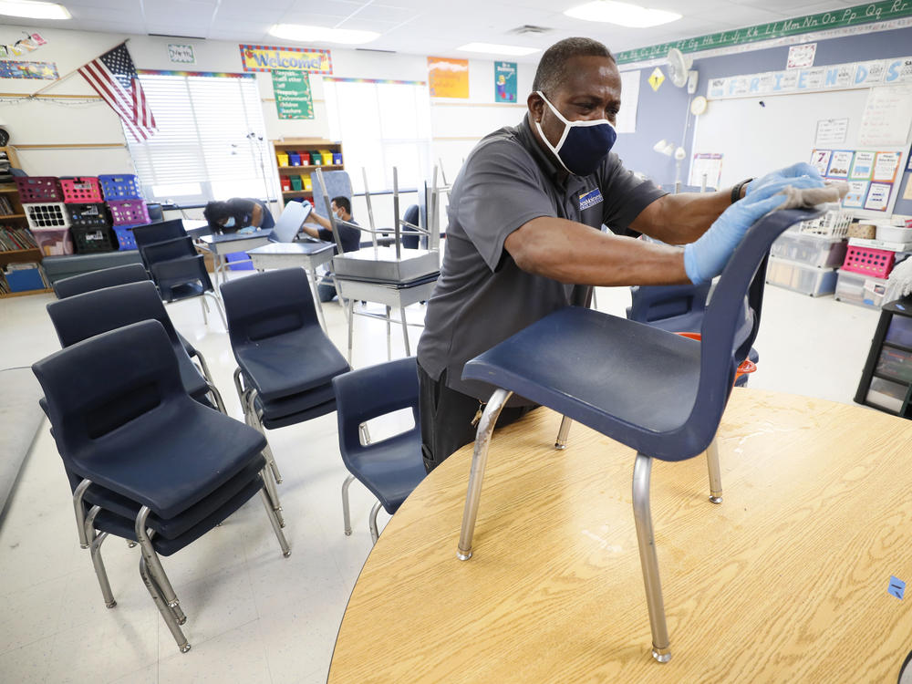 Tracy Harris, a Des Moines Public Schools custodian, cleans chairs at a local elementary school in early July.