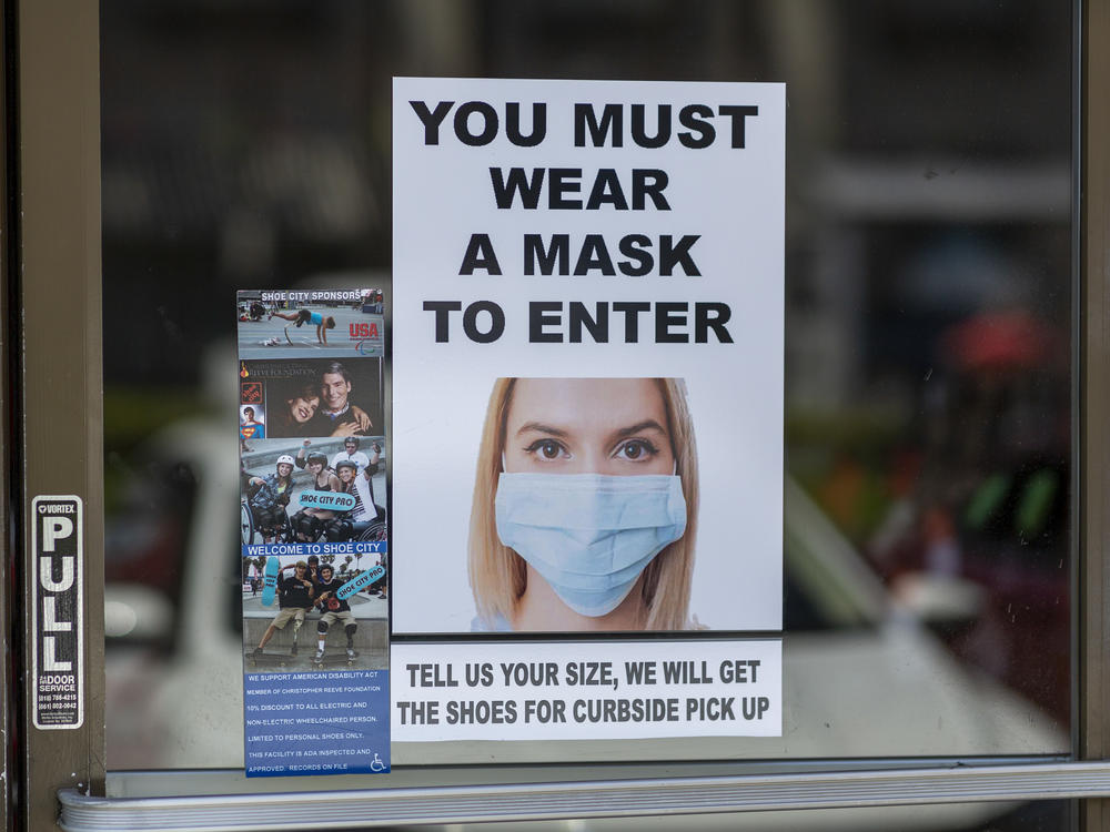 Masks are required for entry to a shoe store in Glendale, Calif. Most people follow guidelines to wear masks when they enter retail stores and restaurants, but some customers don't comply.