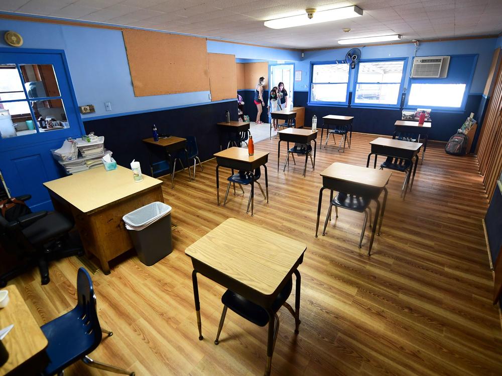 Children in an elementary school class wearing masks enter the classroom with desks spaced apart as per coronavirus guidelines in Monterey Park, Calif.