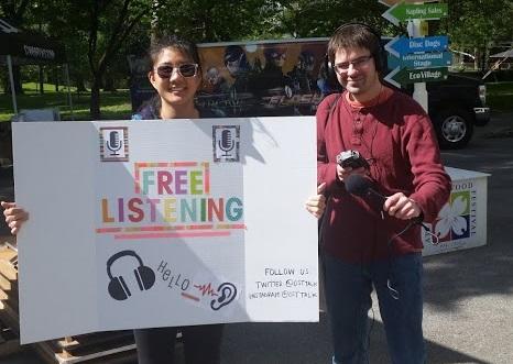On Second Thought producers Linda Chen and Sean Powers hold up their Free Listening Day sign at Piedmont Park in Atlanta.
