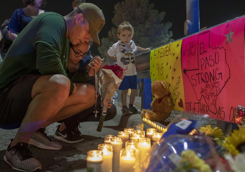 Rene Aguilar and Jackie Flores pray at a makeshift memorial for the victims of Saturday's mass shooting at a shopping complex in El Paso, Texas, Sunday, Aug. 4, 2019. 
