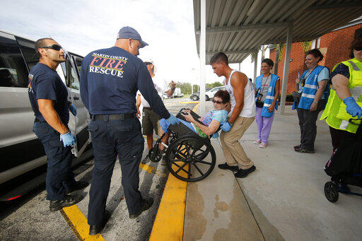 Members of Martin County Fire and Rescue assist evacuees as they arrive at an evacuation shelter for people with special needs, in preparation for Hurricane Dorian, at Dr. David L. Anderson Middle School in Stuart, Fla., Sunday, Sept. 1, 2019.