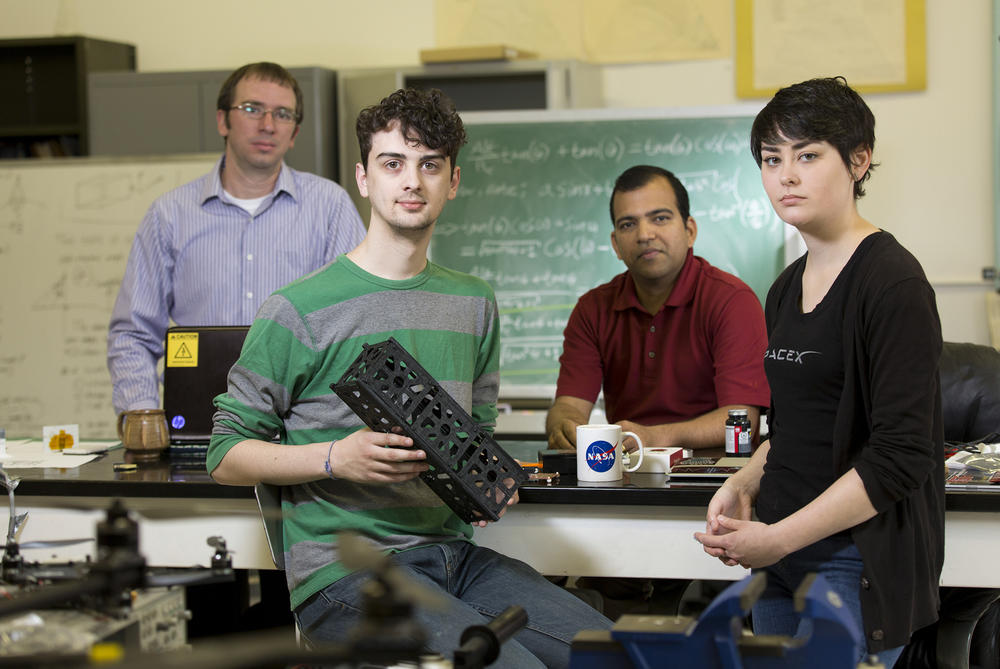 University of Georgia researcher David Cotten, student Caleb Adams, professor Deepak Mishra, and student Megan Le Corre are working with others at UGA to build two cube satellites into space. Adams holds a 3-D printer model of the CubeSat.