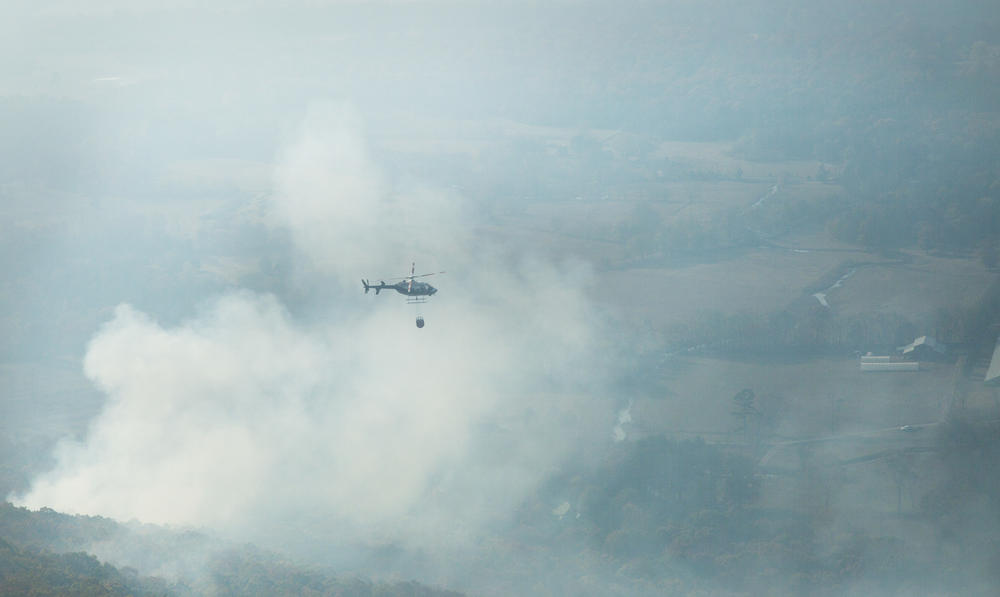 A helicopter carries a load of water to dump on the Tatum Gulf Fire near Rising Fawn, Georgia. 