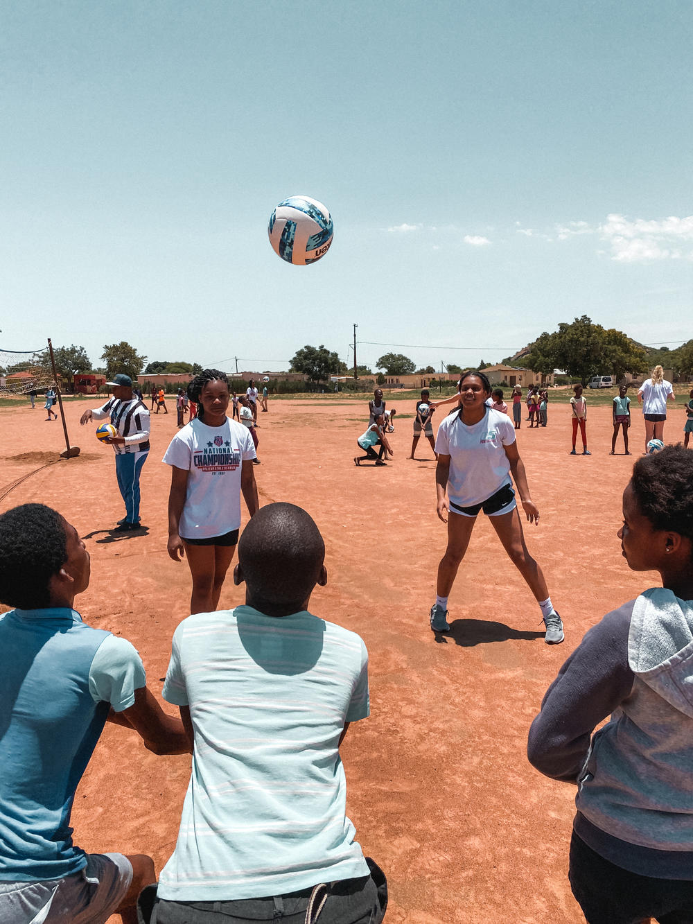 The athletes of the A5 Volleyball Club teaching children from Botswana how to play.