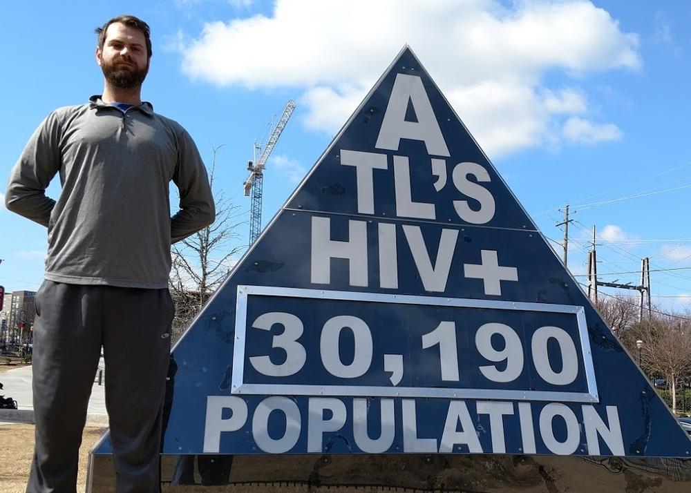 In this Feb. 19, 2017  photo, freelance journalist Matt Terrell stands next to a marker he designed that shows Atlanta's HIV infection rate, which is updated once a week. It is on display outside the Center for Civil and Human Rights in Atlanta.