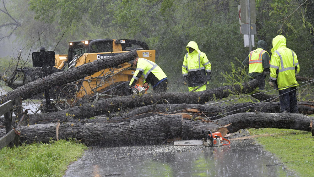 Crew members clean up fallen trees near Avia Riverside Apartments in Roswell, Ga., on April 5, 2017 as dangerous storms battered the Deep South.