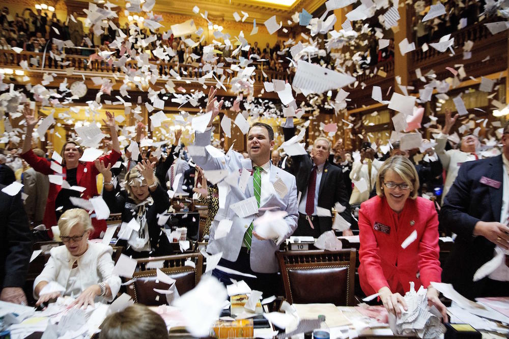 State Rep. Christian Coomer, R-Cartersville, center, and fellow lawmakers throw up paper from their desks at the conclusion of the legislative session in the House chamber, in Atlanta, Friday, March 31, 2017. 