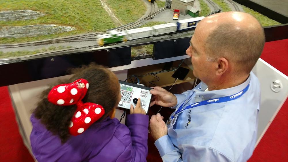 Vic Audo from Illinois-based Horizon Hobby shows Aubriana Davis of Duluth, Georgia how to operate a model train in Atlanta on Jan. 8, 2017.