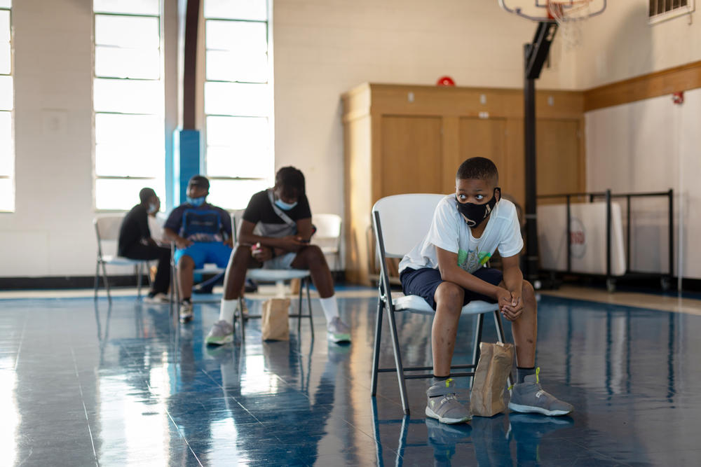 Students enrolled in the summer enrichment program eat breakfast while social distancing in the gymnasium.