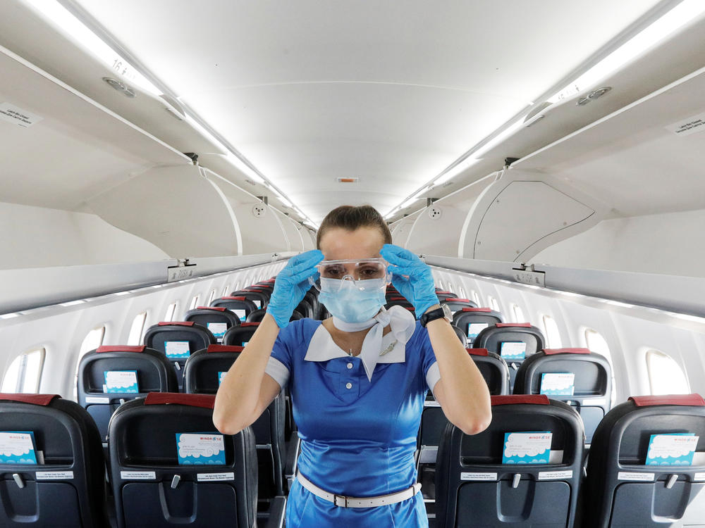 A flight attendant adjusts protective glasses. There has been little documentation about COVID-19 transmission on planes.