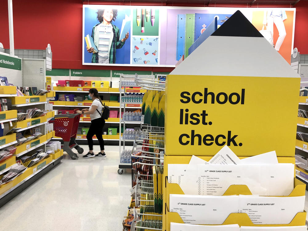 A shopper walks past shelves of school supplies at a Target store in San Rafael, Calif. Preparing for both in-person and virtual learning has families budgeting for new school supplies and bigger purchases.