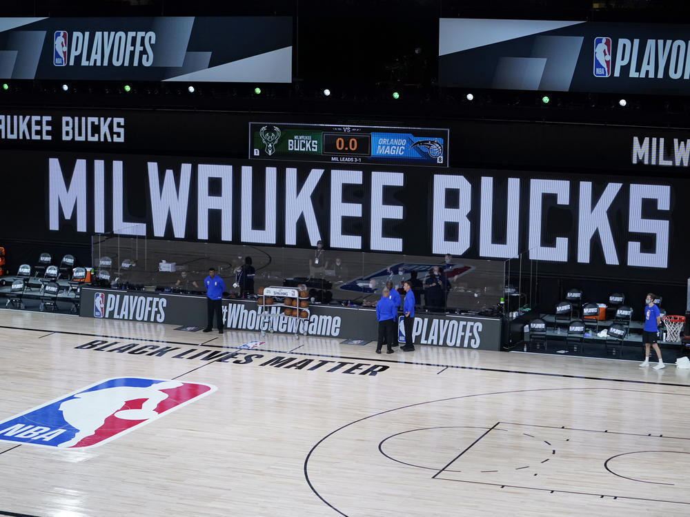 Officials stand beside an empty court at the scheduled start of an NBA playoff game on Wednesday. The Milwaukee Bucks didn't take the floor in protest against racial injustice and the shooting of Jacob Blake.