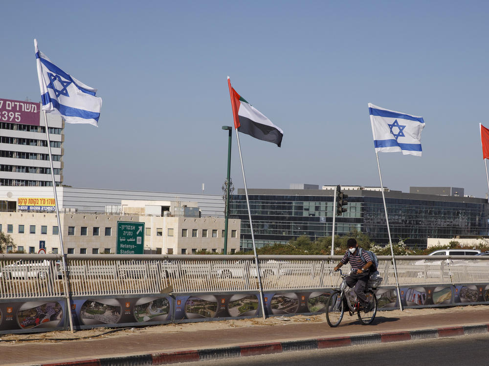 A cyclist rides by Israeli and United Arab Emirates national flags in Netanya, Israel, on Aug. 17.