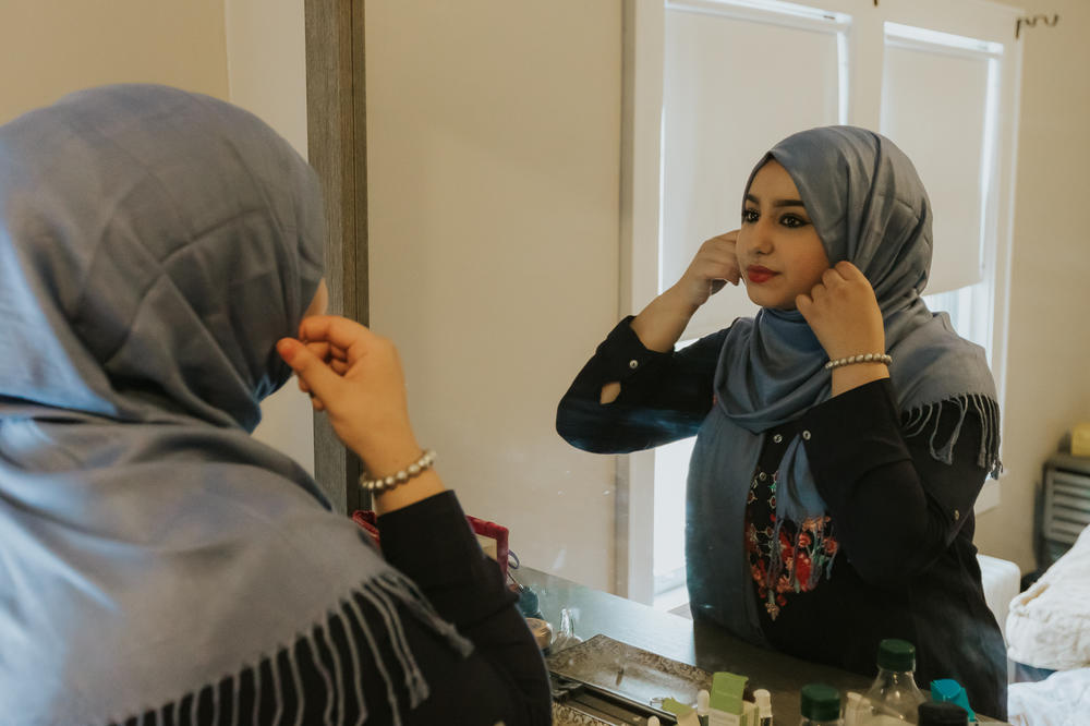 Ammal, 18, adjusting her hijab in the mirror.