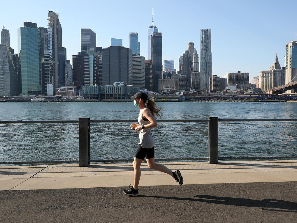 A woman runs with her face mask on Monday in New York City, where the mayor has announced that city personnel will hand out free masks to anyone who is not wearing a face covering.
