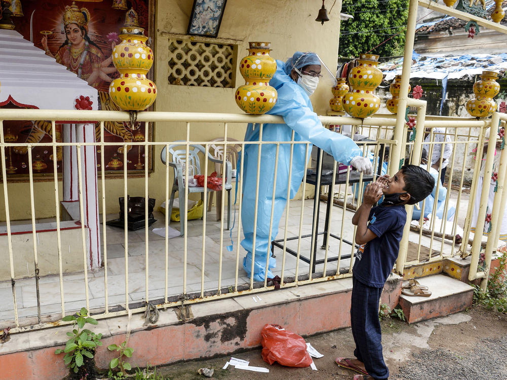 A health worker collects a swab sample from a boy for a coronavirus test at a temporary collection center at a Hindu temple in Hyderabad, the capital of the Indian state of Telangana, on Sept. 30, 2020.