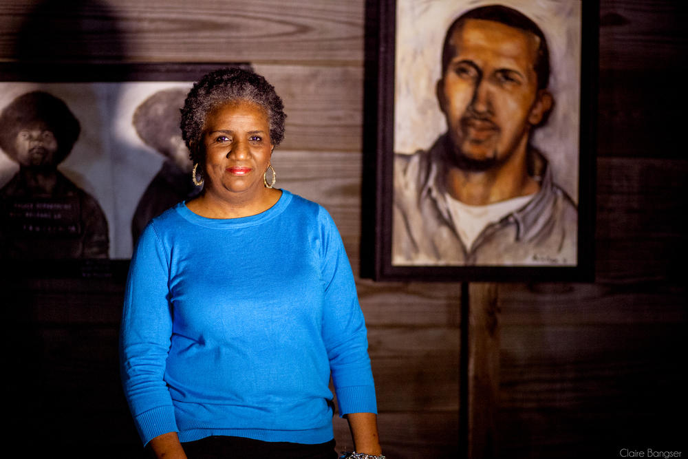 Mac's mother, Sheila Phipps, stands with a portrait she painted of her son, part of a series called Painted Justice, depicting prisoners who were wrongfully or harshly accused.