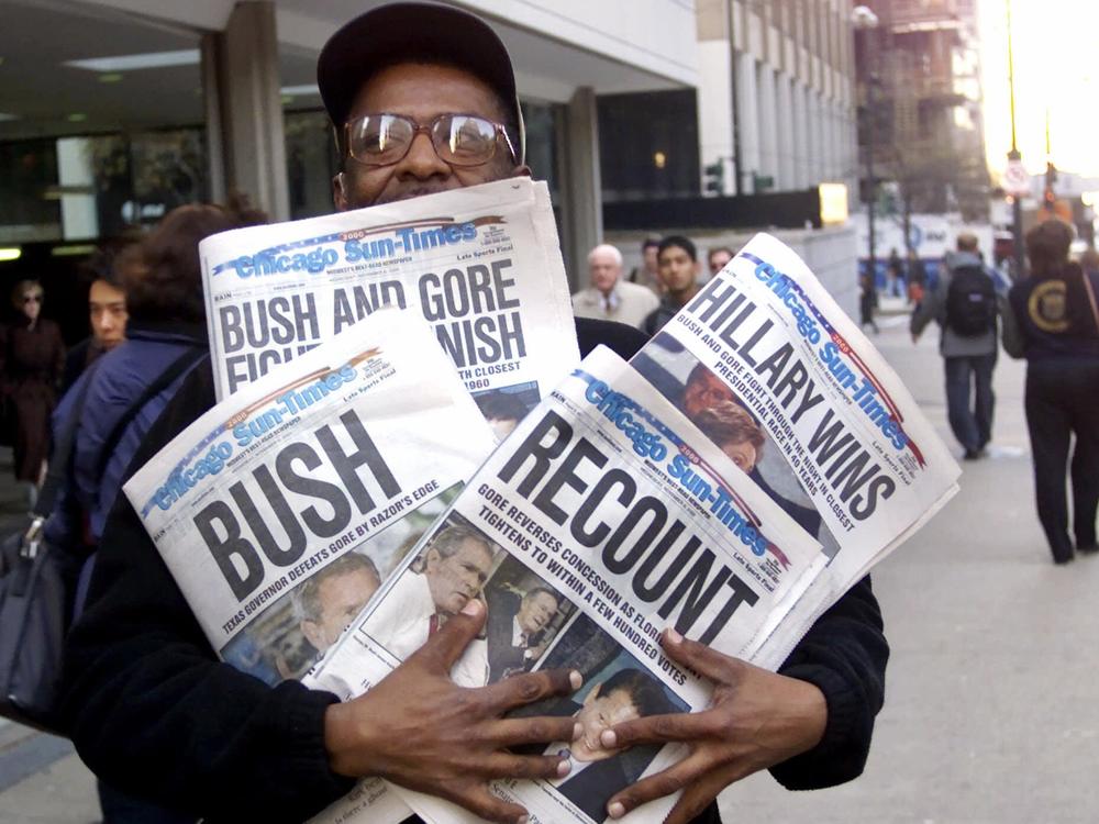 A man holds four copies of the Chicago Sun-Times, each with a different headline, on Nov. 8, 2000.