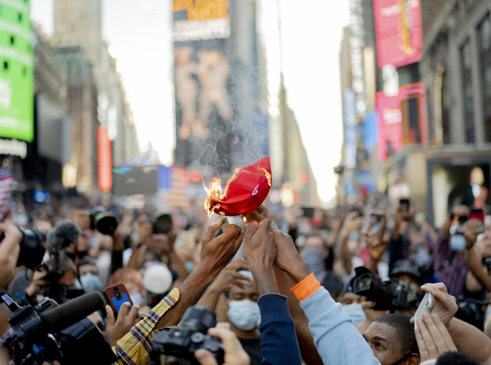 <strong>NEW YORK CITY, NY:</strong> People in Times Square burn a MAGA hat.