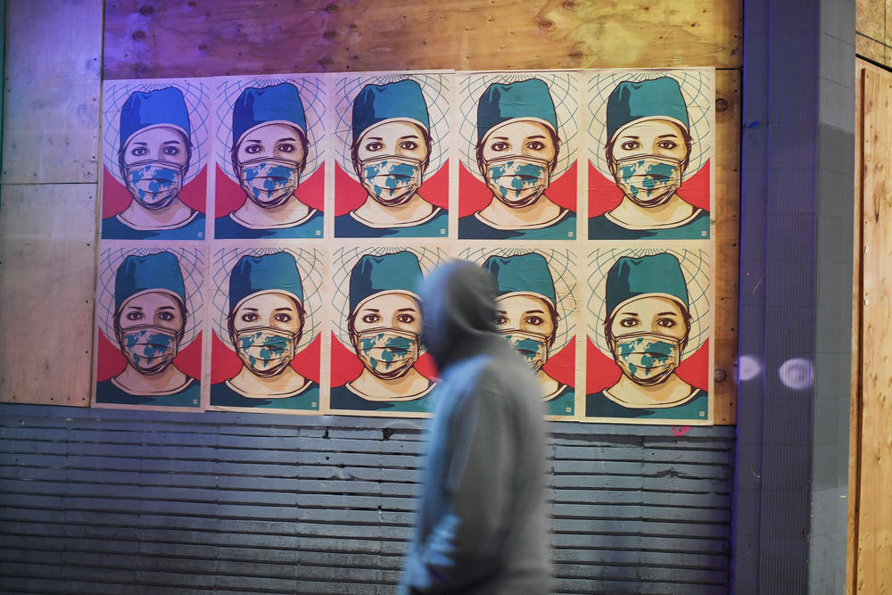 A pedestrian walks past posters showing a health care worker wearing a mask in Los Angeles. California became the second state to surpass 1 million coronavirus infections last week.