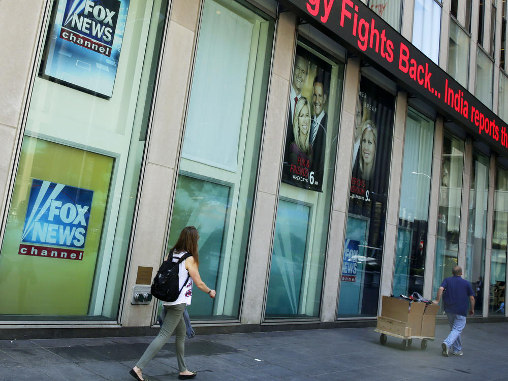 People pass the News Corporation headquarters building and Fox News studios in New York.