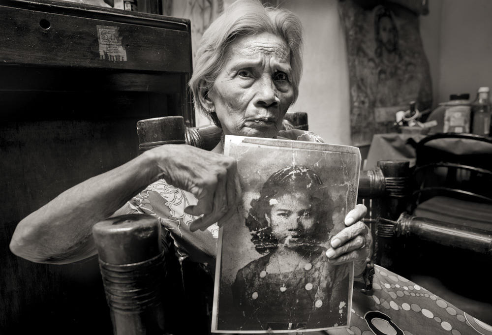 Fedencia Nacar David holds her photo for an application to work as a maid. She was 15. A year before, a Japanese soldier sliced her ear and threatened to behead her if she didn't go to a garrison with him; she was raped over 10 days. 