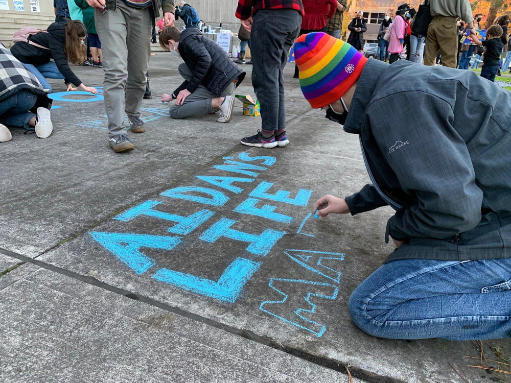 Toren McKnight of Central Point draws on the cement at the vigil for Aidan Ellison outside the Jackson County Courthouse in Medford, Ore., on Dec. 3.