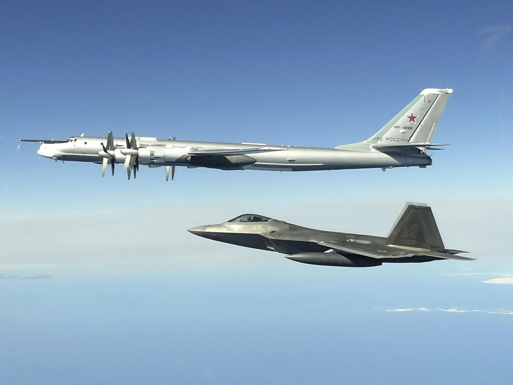 In this image taken June 16, 2020, and released by the North American Aerospace Defense Command, a Russian Tu-95 bomber (top) is intercepted by a U.S. F-22 Raptor fighter off the coast of Alaska. Russian nuclear-capable strategic bombers have flown near Alaska on a mission demonstrating the military's long-range strike capability.