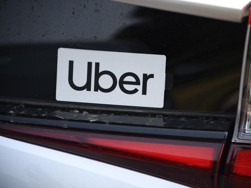 An Uber sticker is seen on a car at the start of a protest by ride share drivers on Aug. 20, in Los Angeles. Uber said it will sell its self-driving research unit to startup Aurora.